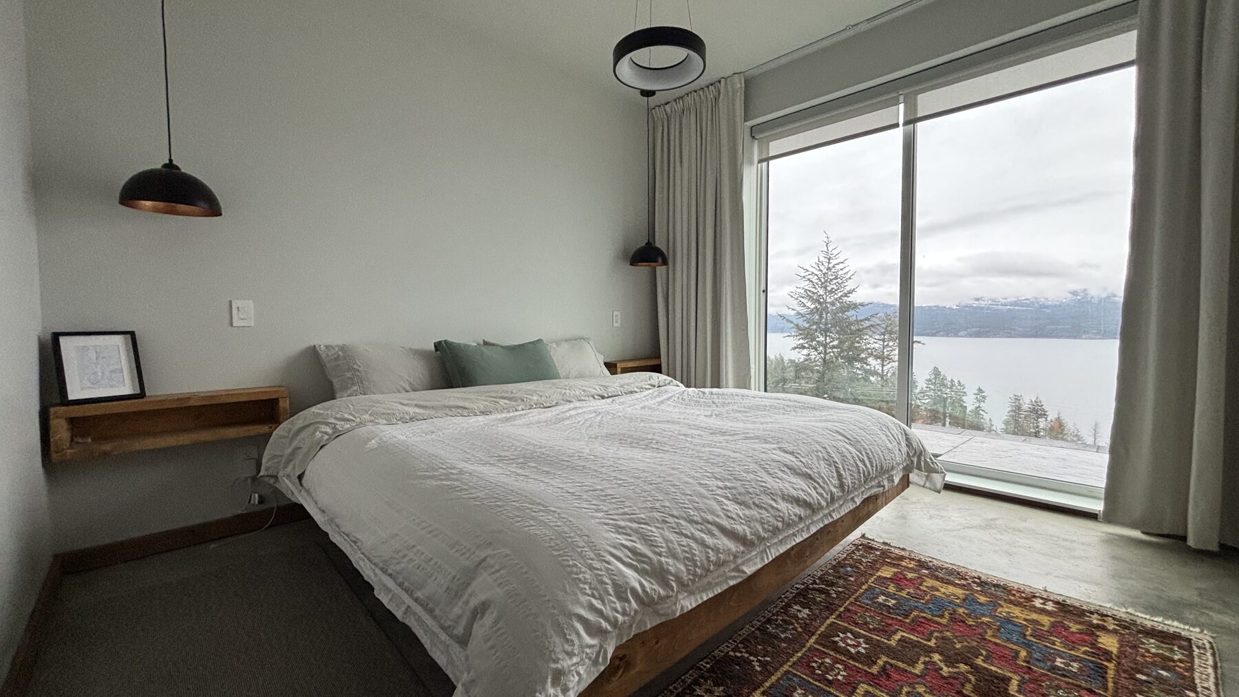Bedroom with floor-to-ceiling windows looking out over the lake