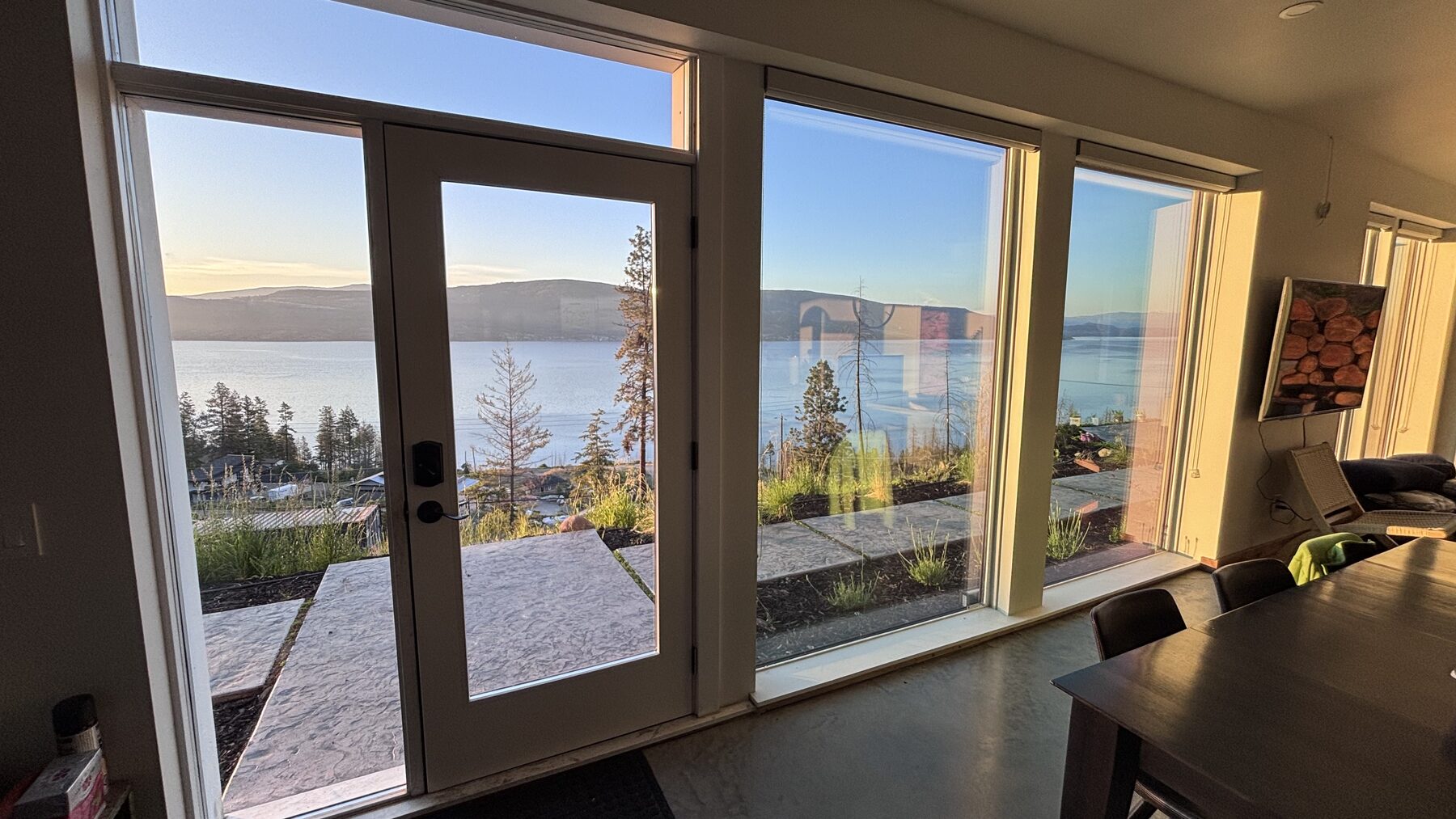 Dining table beside sliding doors open to the lake at sunrise