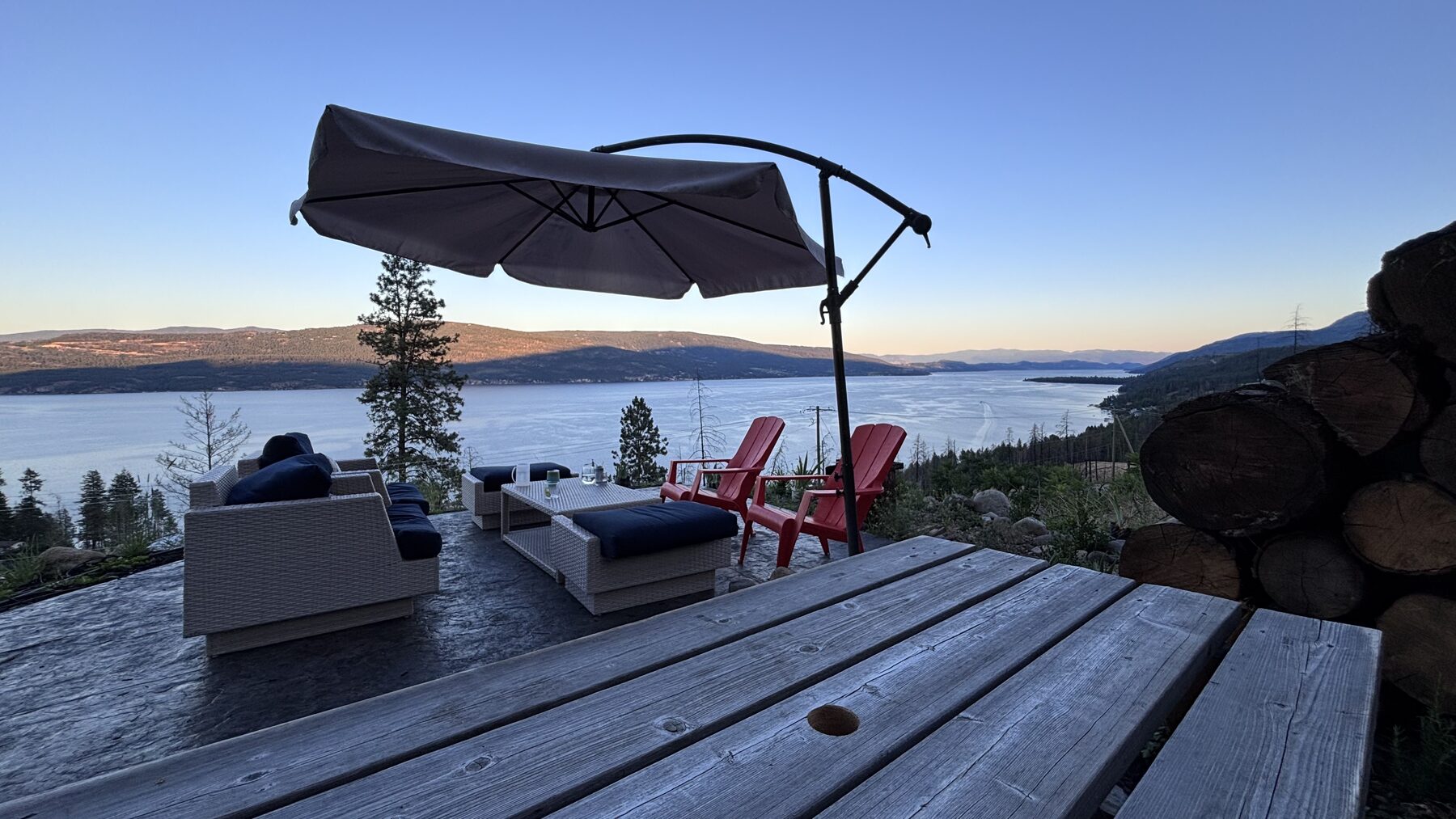 Outdoor patio lounge furniture overlooking Okanagan Lake at dusk